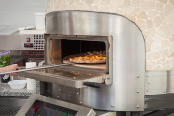 cook pulls lave baked pizzas from a stone oven