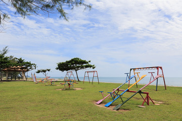Colorful playground on yard in the park near the beach with clouds and sky background