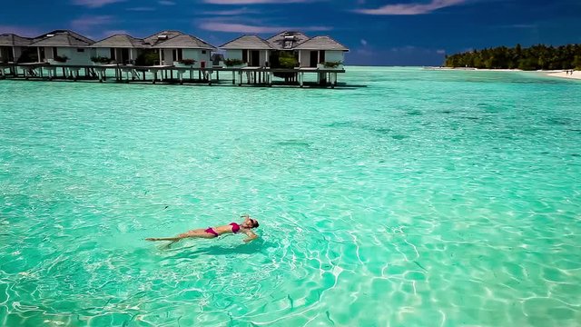 Young woman swimming in a coral lagoon, Maldives.