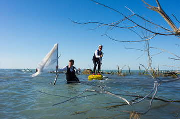 Naklejka premium Two businessmen with a yellow suitcase and white flag, in an extreme journey through the ocean.