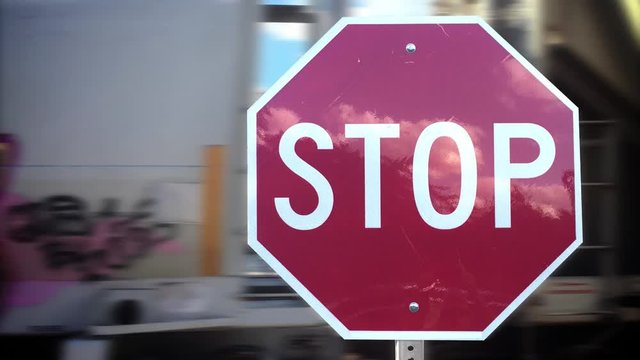 A red stop sign at a railroad crossing while a cargo train passes behind. With audio.  	