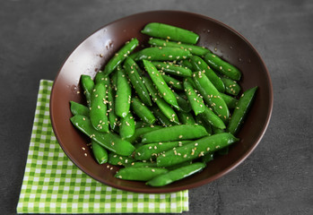 Fresh peas in brown bowl on grey background