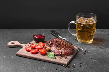 Tasty steak with tomatoes and beer on cutting board