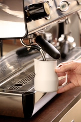 Barista whipping milk in coffee machine