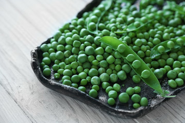 Fresh green peas on a black tray