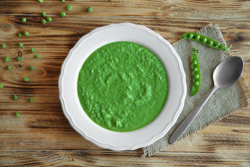 Green pea soup in plate on wooden table