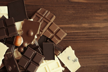 Chopped chocolate bars with nuts on wooden background