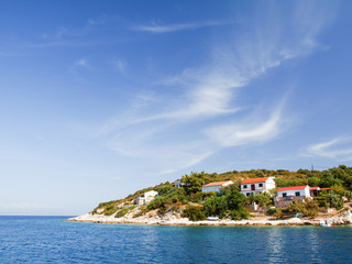Seascape with beautiful island and with cozy homes, blue sky and