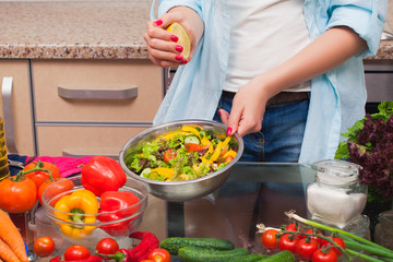 The girl's hands squeezed the lemon into the salad