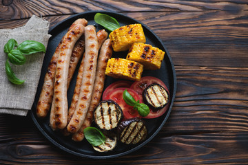 Grilled sausages and vegetables served in a frying pan, top view