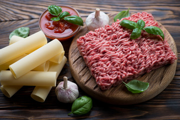 Uncooked cannelloni, raw minced meat, tomatoes, garlic and basil