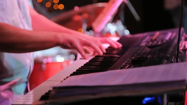 Musician skilfully plays on synthesizer during night party.