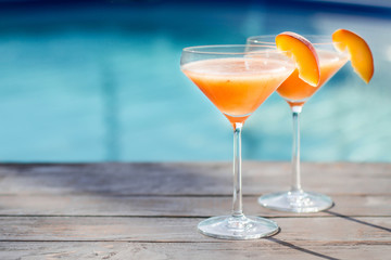 Bellini cocktail with peach isolated near pool