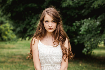 Fototapeta na wymiar portrait of beautiful young brunette woman in the nature. spring, summer. girl brown hair with blue eyes and with long hair in white summer dress