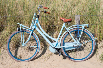 Fototapeta na wymiar blue bike parked in the dunes at the Dutch North Sea coast