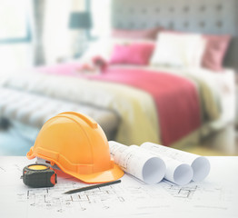 architectural blueprint with safety helmet and tools over bedroom with red scheme color decoration