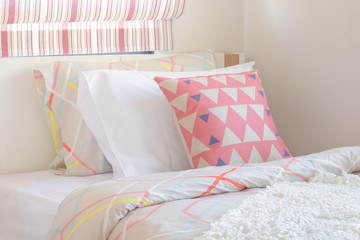 Pink triangle pattern pillow setting on bed at the corner of sweet color style bedroom