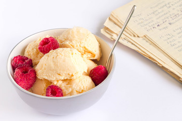 Vanilla ice cream with fresh raspberries. Family cookbook in the background