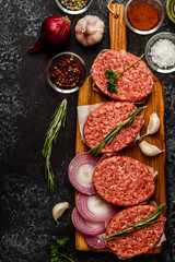Raw ground beef meat steak cutlets with herbs and spices.