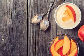 Homemade yogurt with fresh peaches on a wooden background.