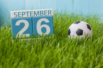 September 26th. Day 26 of month, wooden color calendar on green grass lawn background. Autumn time. Empty space for text