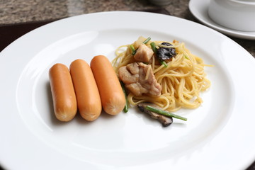 Puff yellow noodles with chicken meat and pork sausage on white