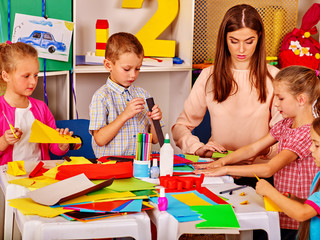 Children with teacher making something out of colored paper in primary school. Children paper craft...