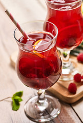Top view on wooden boards ice cold glasses with red raspberry lemon cocktail . Alcohol cocktail three hundred and thirty one with raspberry and lemon.