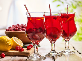 On wooden boards are ice cold beverage glasses with red raspberry lemon cocktail . Alcohol red berry cocktail number three hundred and thirty two.