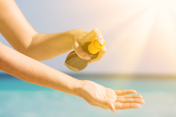 Woman applying sunscreen protection cream against turquoise cari