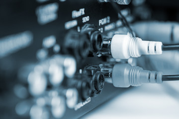 Rca cables on back panel of dj mixer. Blue tone