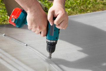 Worker screwing screw into polycarbonate