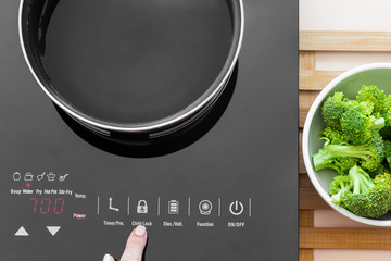 Woman showing on child Lock button on Induction stove
