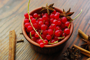 Red currant berries in a clay bowl with orange slice, christmas spices, anise and cinnamon sticks...