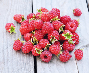 Handful of fresh ripe raspberries on rustic wooden background, gardening and healthy food concept