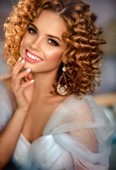 Beautiful young woman in the wedding dress  with  curly hair .  Model girl with a charming smile .