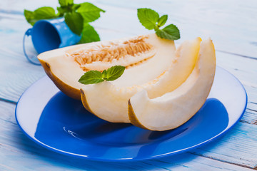Fresh sweet melon in blue plate on the white wooden table