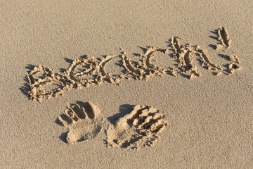 Inscription Beach and handprints on sand