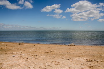 Calm sea, white clouds, yellow sand