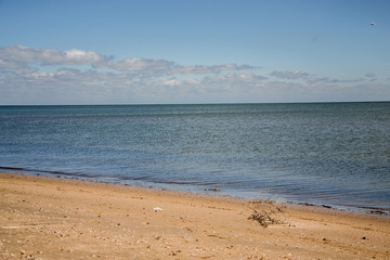 Calm sea, white clouds, yellow sand