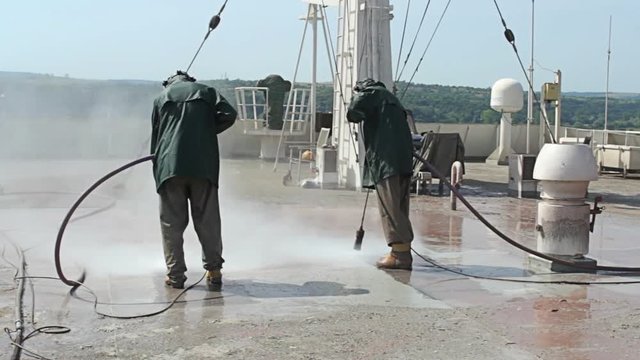 Shipyard Workers repairing and painting new layer of paint on modern ship