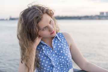 Sad young woman holding head and thinking at riverside