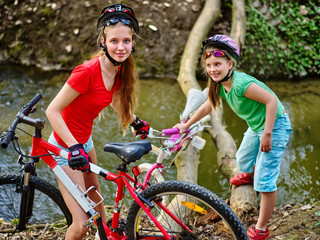 Children girl with bicycle. Girls rides bicycle. Girls sister cycling fording throught water on log. Cycling trip is good for health. Cyclist watch at camera down up.