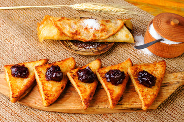 Toast with jam, sugar bowl and pancake on a plate.