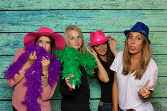 Junge Mädchen mit Hüte und Federboas strecken die Zungen heraus - Photobooth Party