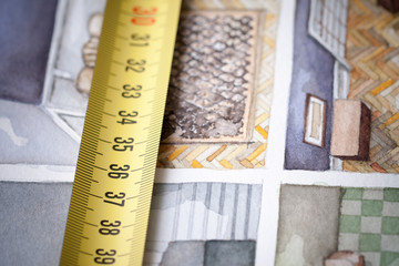 Yellow measuring tape in centimeters shot as macro image on the background of watercolor floorplan sketch painting symbolising artistic approach in designing and building house interior space