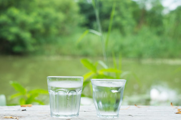 Cool water on wooden desk with Lake background