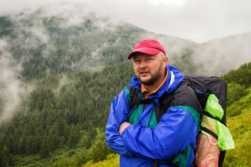 Portrait man hiker with backpack in Carpathian mountains, summertime journey