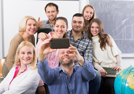  students of different age doing group selfie on smartphone