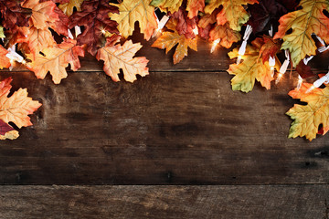 Rustic fall background of autumn leaves and decorative lights over a rustic background of barn...